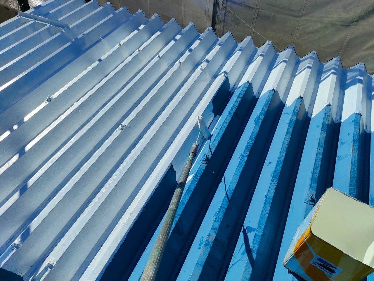 名古屋市の折半屋根塗装。錆止めを塗っている作業写真