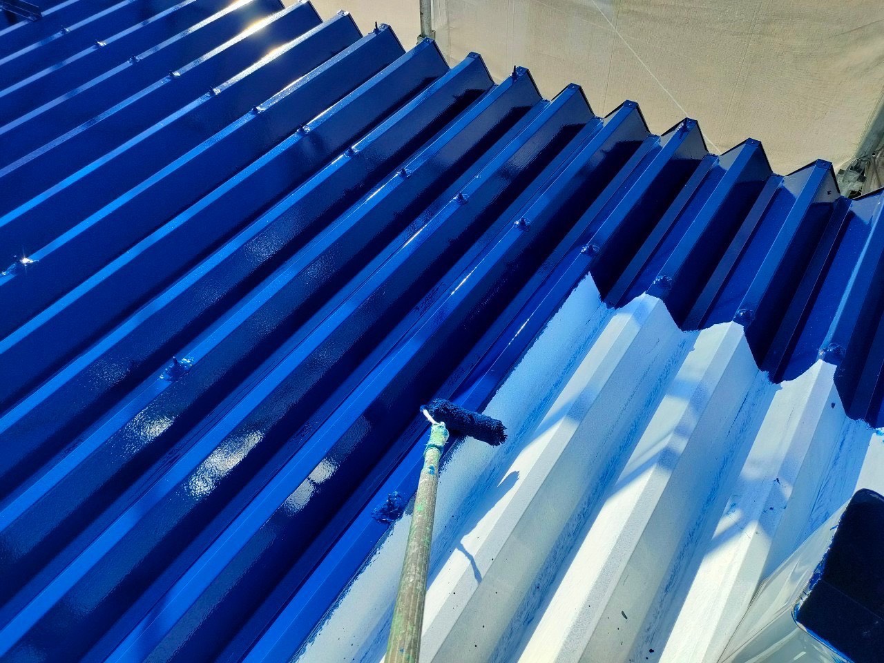 名古屋市の折半屋根塗装。ルーフスターSiで屋根を塗っている作業写真