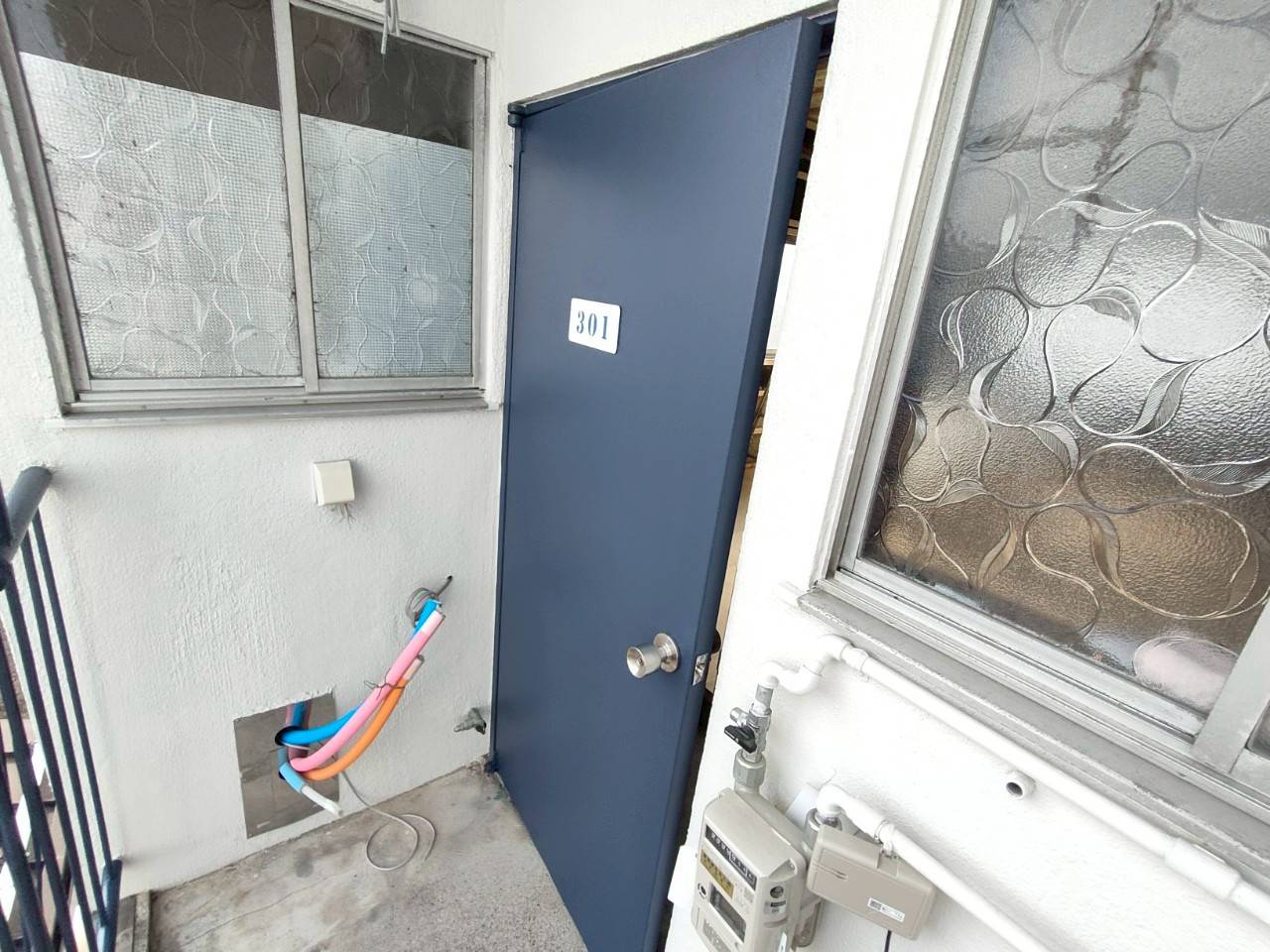 岐阜市のマンション修繕における玄関ドア塗装完了後のアフター写真。75-30Dのネイビーで美しく塗り替えられた301号室の鉄扉。