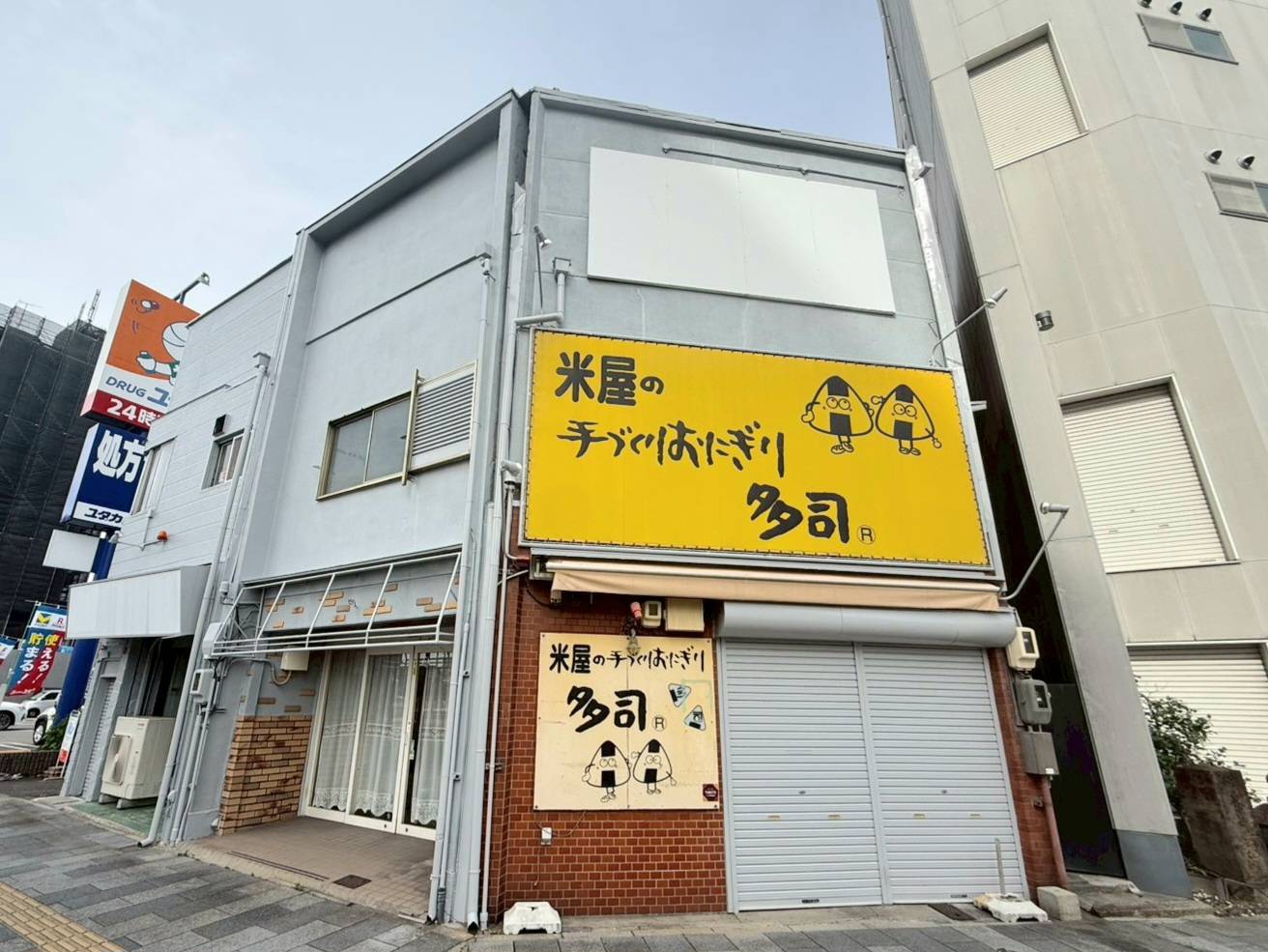 名古屋市西区の店舗塗装完了後の完成写真。水性セラミシリコン（N-70）で美しく仕上げた2階建て店舗ビルのおにぎり店側外観。