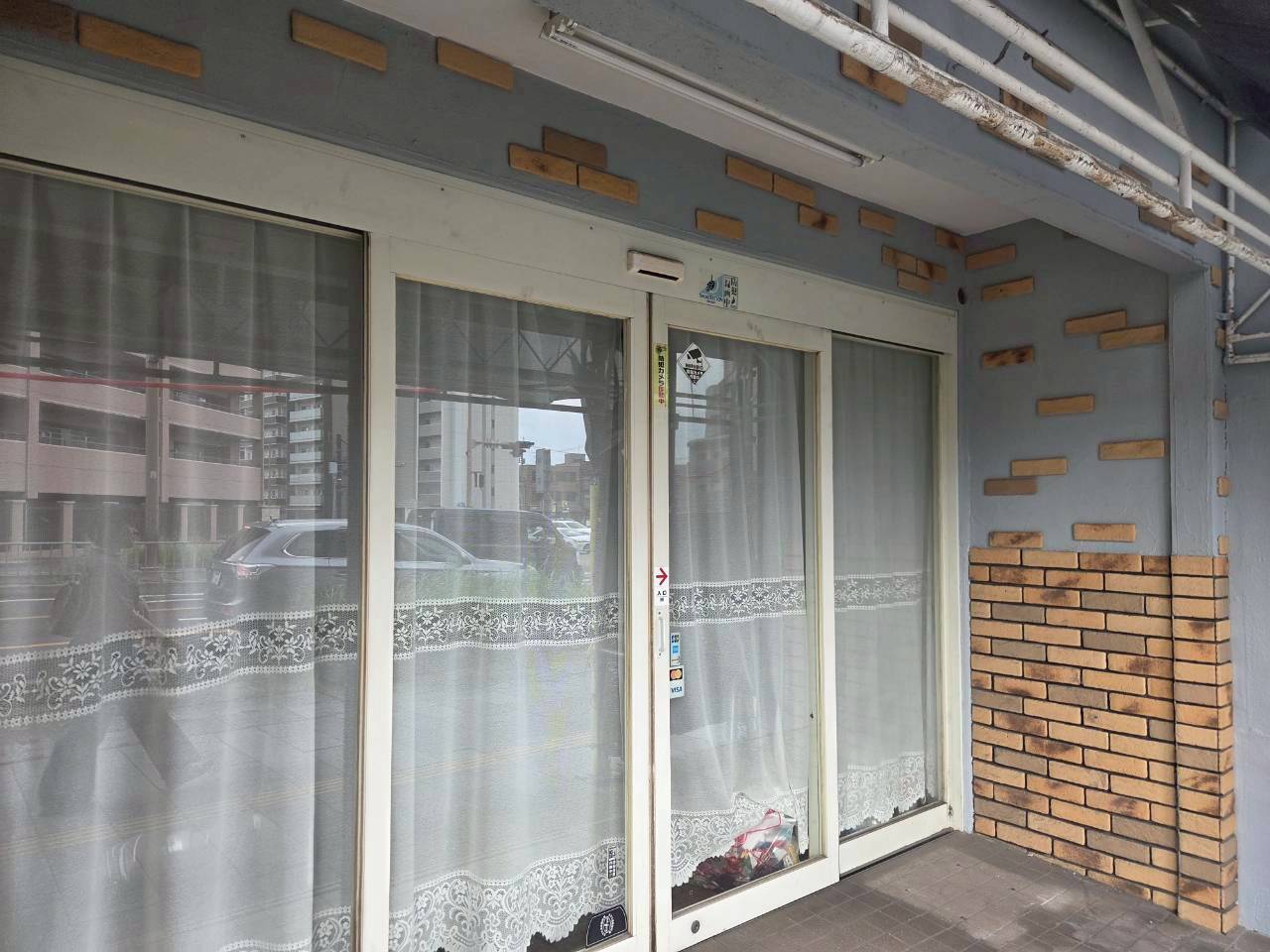 名古屋市西区の店舗塗装完了後の完成写真。水性セラミシリコン（N-70）でサッシ周りやレンガ調アクセント壁を美しく塗り分けた1階入り口。