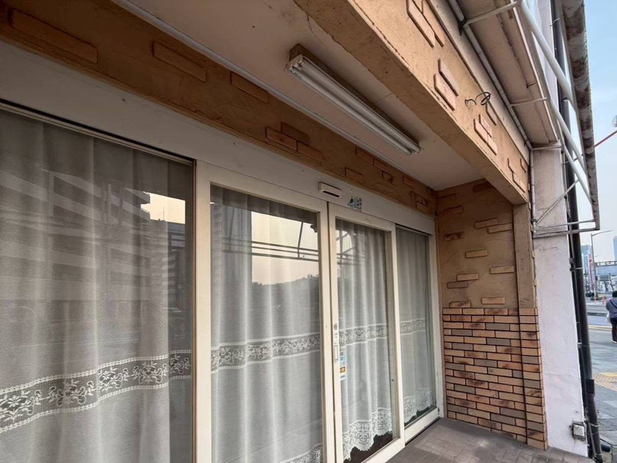 名古屋市西区の店舗塗装前の施工前写真。経年劣化で茶色く色あせや黄ばみが見られる1階入り口まわりの外壁。